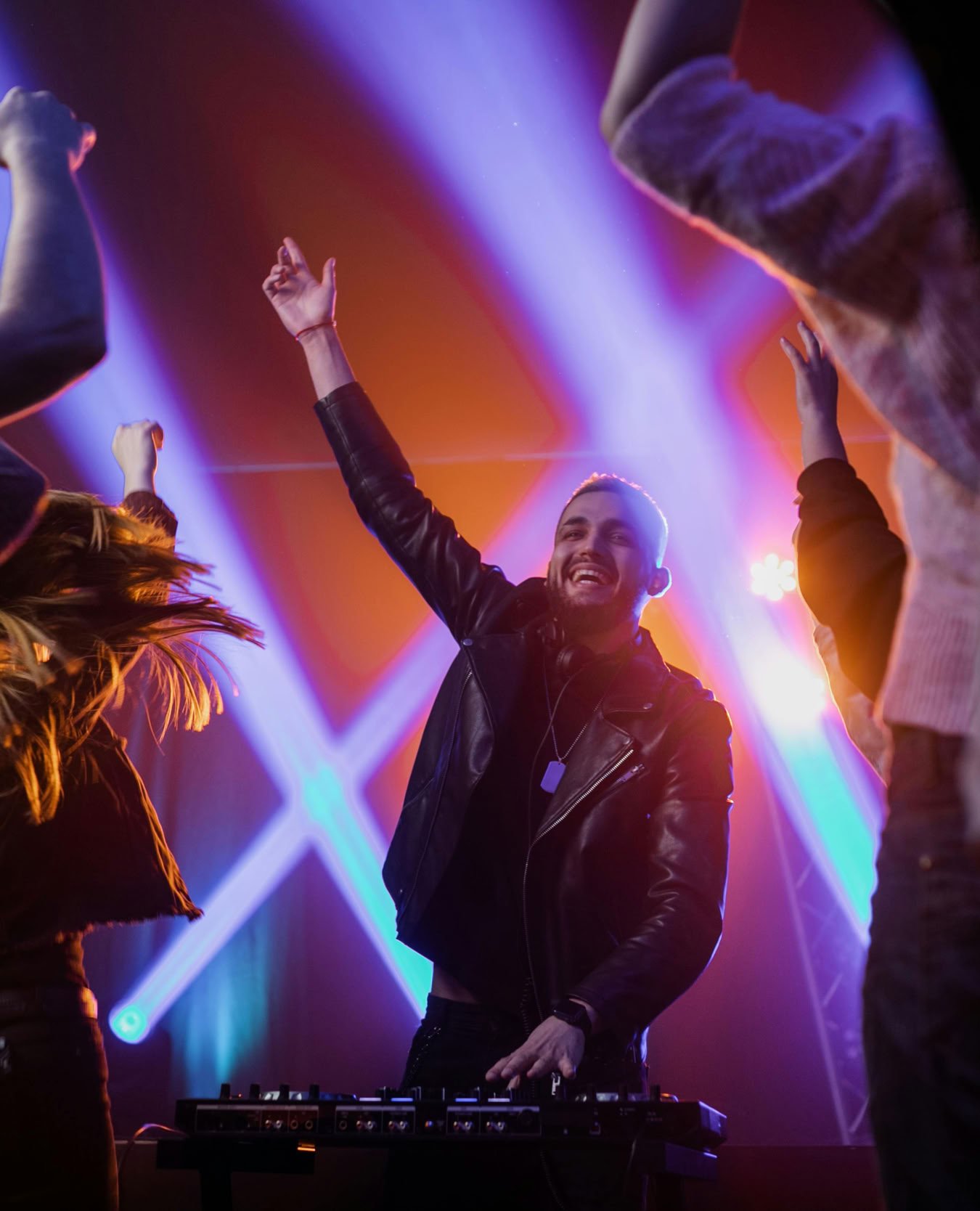 DJ performing live in a vibrant nightclub with an energetic crowd dancing under colorful lights.